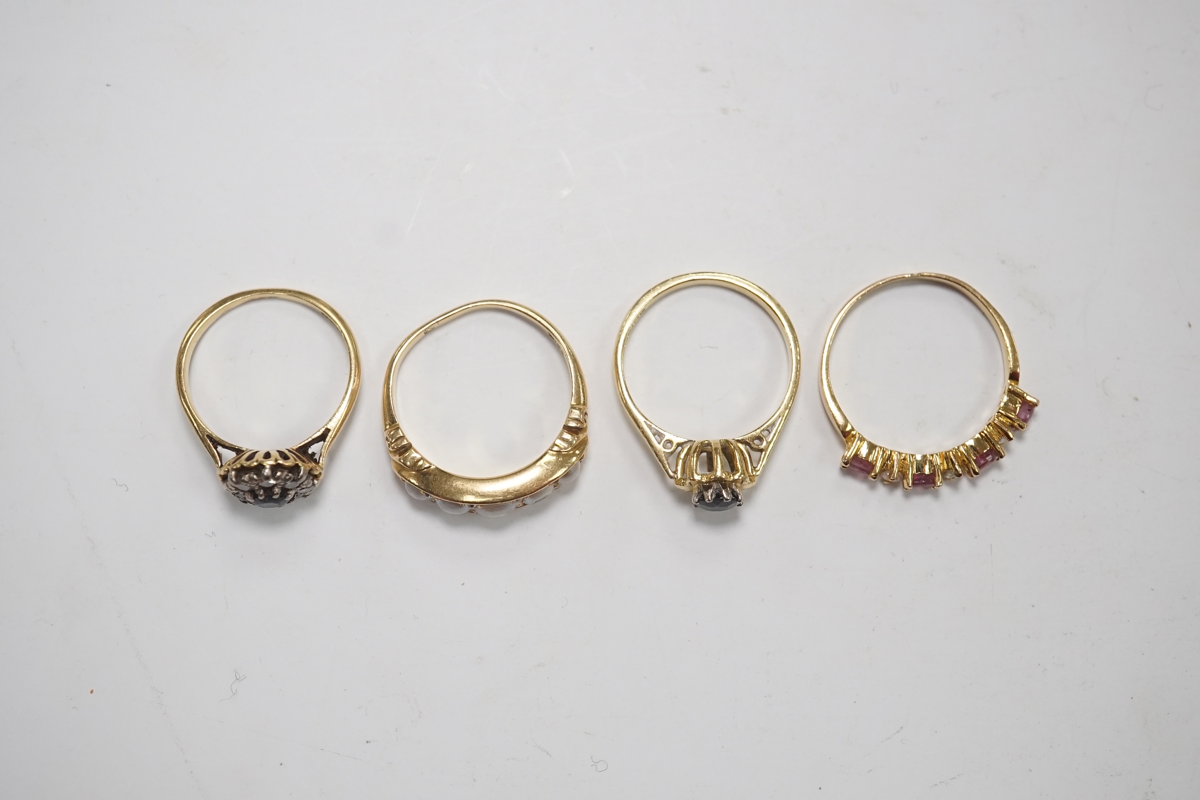 A late Victorian yellow metal and five stone split pearl set half hoop ring, with diamond chip spacers, size N/O, two modern 18ct gold and gem set rings and one other ring. Condition - fair to good